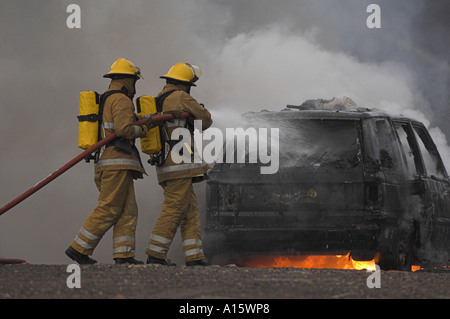 Zwei Feuerwehrleute, die Bekämpfung von einem brennenden Auto. Stockfoto