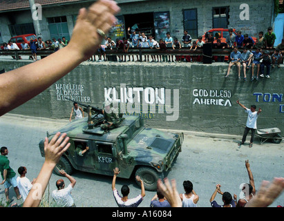 Ethnische Albaner grüßen amerikanische NATO-Truppen, wie sie durch die Stadt Gjilan Mittwoch, 30. Juni 1999 im Kosovo fahren. Stockfoto