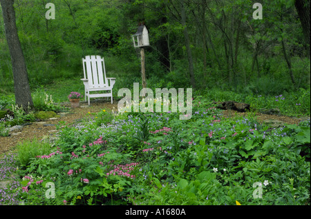 Schatten-Garten mit weißen Adirondack Stuhl und skurrilen Vogelhaus in Haus Garten, Midwest USA Stockfoto