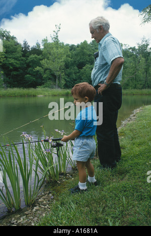 Großvater und Kleinkind Enkel stehen an der Seite eines Sees im Sommer mit Angelruten miteinander, in Missouri Stockfoto