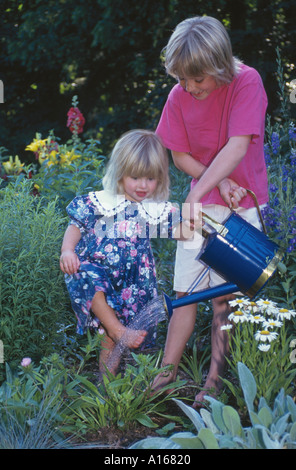Zwei Mädchen, in der Familie, mit einem blauen Gießkanne und mit den Füßen im Garten sauber, Missouri USA Stockfoto