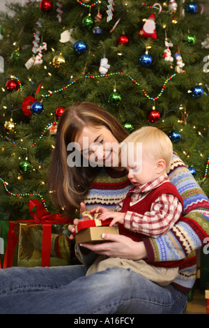Eröffnung Weihnachtsgeschenk mit einjährigen Sohn Mutter Stockfoto
