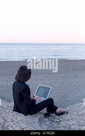 Frau in Businesskleidung arbeiten auf Laptop-Computer sitzen am Strand Stockfoto