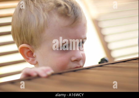 kleiner Junge neugierig am Tisch stehen Stockfoto