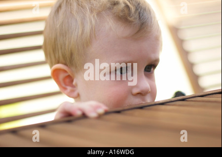 kleiner Junge neugierig am Tisch stehen Stockfoto