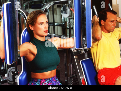 Attraktive junge Frau und in der Mitte im Alter Mann in einem Fitnessstudio Gewichte zu heben Stockfoto