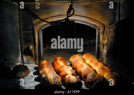 Ein Bäcker entfernt frisch gebackenes Brot aus seinem Holzofen, Malta. Stockfoto