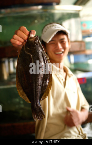 Lächelnd Mann halten Fisch, Fischmarkt, Qizha Jie, Ningbo, China. Stockfoto