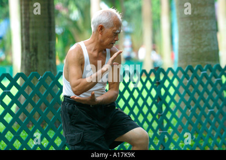 Ein älterer Mann praktiziert Tai Chi in einem Park in Hong Kong. Stockfoto