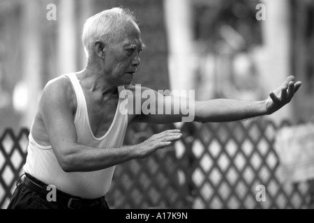 Ein älterer Mann praktiziert Tai Chi in einem Park in Hong Kong. Stockfoto