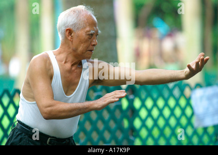 Ein älterer Mann praktiziert Tai Chi in einem Park in Hong Kong. Stockfoto