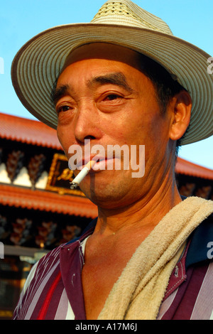 Ein glücklicher chinesischen Mann lächelt, als er eine Zigarette raucht. Stockfoto