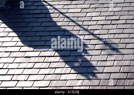 DER SCHATTEN VON EINEM SCHORNSTEIN WIRFT EINEN SCHEINBAR DÄMONISCHEN SCHATTEN ÜBER EIN SCHIEFERDACH UK Stockfoto