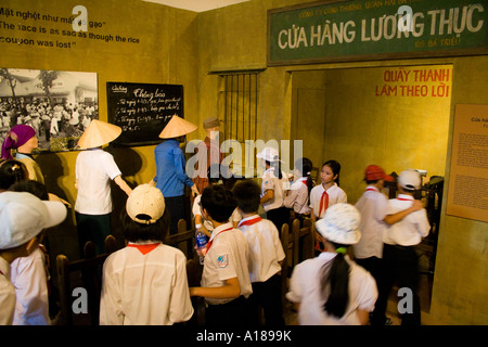 2007 Foto Bild uniformierten Schulkinder Spaziergang durch eine Anzeige auf Ration Karte Linien in frühen Tagen der Kommunismus von Vietnam Stockfoto