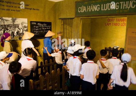 2007 uniformierten Schülerinnen und Schüler gehen über ein Display im Ration Karte Linien in frühen Tagen der Kommunismus von Vietnam Stockfoto
