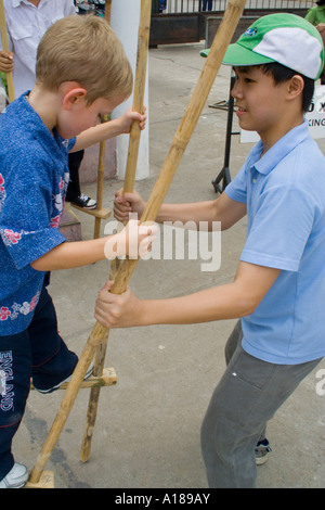 Vietnamesische junge 2007 hilft American Boy Spaziergang auf Stelzen Vietnam Museum für Völkerkunde Hanoi Vietnam Stockfoto