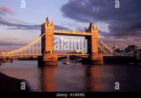 Tower Bridge, London, UK bei Sonnenuntergang mit Brückenbauwerk und Wolken beleuchtet von Einstellung Sonne entnommen am Fluss in der Nähe von Tower of London Stockfoto