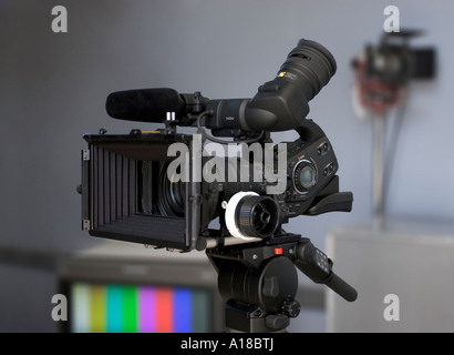 High-Definition-Video-Kamera in einer Studioumgebung mit professioneller Beleuchtung und einem Broadcast-TV-Monitor im Hintergrund Stockfoto