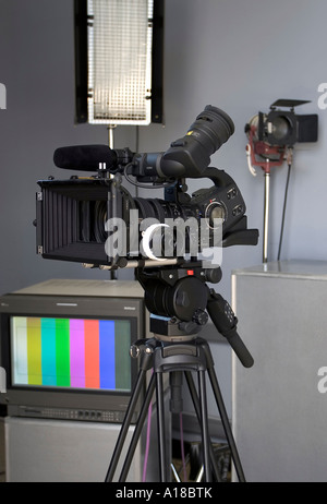 High-Definition-Video-Kamera in einer Studioumgebung mit professioneller Beleuchtung und einem Broadcast-TV-Monitor im Hintergrund Stockfoto