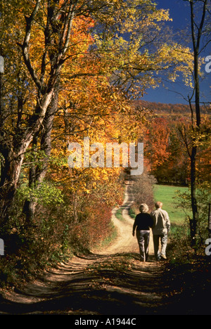 Älteres Paar zu Fuß entlang der unbefestigten Straße gesäumt von Herbstfarben Stockfoto