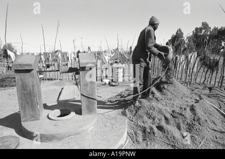 B/W eines Mannes, der die Vertiefung eines Wasserfalles unterstützt, um den Wassertisch während einer langen Dürreperiode zu erreichen. Nr. Kwekwe, Simbabwe Stockfoto