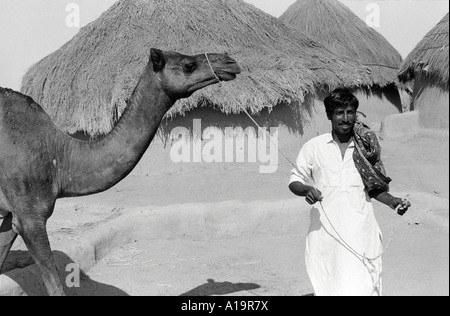 S/W eines Dorfbauern, der sein Kamel in die trockene Wüstenregion von Tharparkar, Pakistan, führt Stockfoto