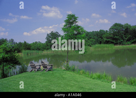 Zwei verwitterte Adirondack Stühle auf dem Rasen See an Sommertagen, Missouri USA Stockfoto