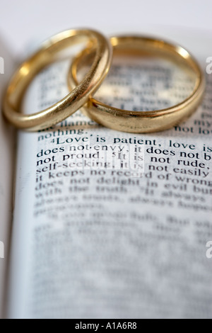 Zwei goldene Hochzeit Ringe liegen auf eine aufgeschlagene Bibel. Die Verse sind von 1. Korinther 13. Stockfoto