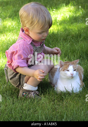 Kleiner Junge im Dirndlrock mit einer Katze - Kleiner Junge in Bayerischer Tracht Mit Katze Stockfoto