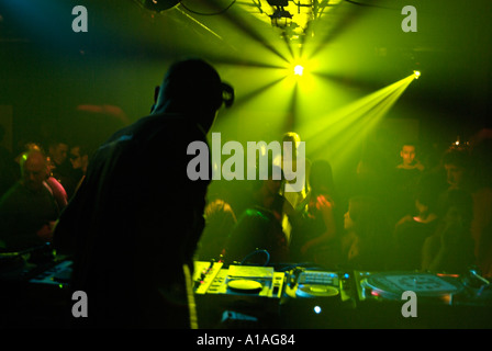 Club DJ hinter den Decks einer überfüllten Diskothek. Stockfoto