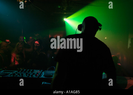 Club DJ hinter den Decks einer überfüllten Diskothek. Stockfoto