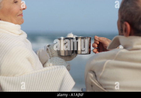 Älteres Paar mit einem Drink am Strand Stockfoto