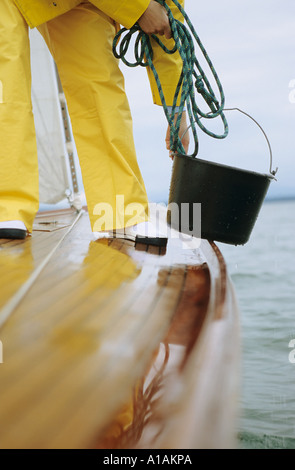 Person auf dem Deck des Bootes mit Eimer und Seil Stockfoto