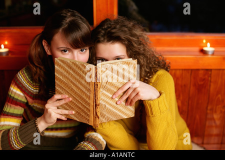 Zwei Frauen, die über einem Buch spähen Stockfoto