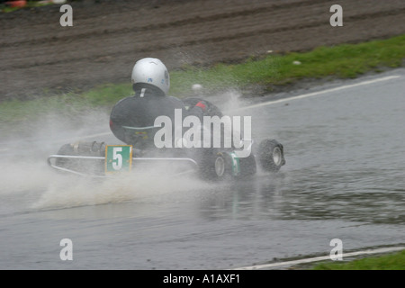 World Formula Kartfahrer durchläuft einen Spritzer Wasser in einem nassen Nutts Corner Motorsport Circuit County Antrim Nordirland Stockfoto