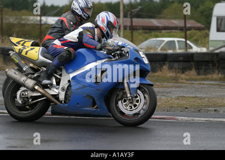 zwei Motorradfahrer Rennen unter einer Kurve in einem nassen Aghadowey Motorsport Circuit County Antrim Nordirland Stockfoto