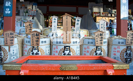 Fässer von Sake auf dem Display vor eine Spendenbox im Fushimi Inari-Taisha-Schrein in Kyoto Japan Stockfoto