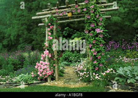 Summers Pastell Gartentor - handgemachte Garten Laube mit Birdbox und Reben von blühenden Rosen und Clematis Blumen, USA Stockfoto