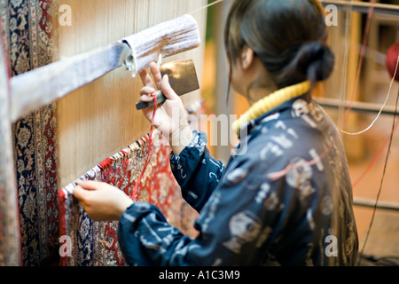 CHINA XI weibliche chinesische Handwerker Beratung Chart Muster bestimmen beim Weben eine orientalische Wolldecke Stockfoto