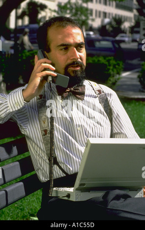 Mann mit Mobiltelefon und Compaq-Notebook-Computer mit drahtlosen Modem auf Parkbank in der Innenstadt von Washington DC Stockfoto