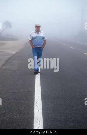 Mann zu Fuß weiße Linie entlang Foggy Street Stockfoto