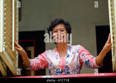 Frau öffnet louvered Fensterläden am historischen Baba House Hotel Chinatown Malacca Malaysia Stockfoto