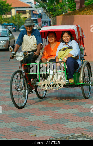Rikscha mit zwei Frauen Passagiere auf Straße in der Nähe von Dutch Square Melaka Stockfoto