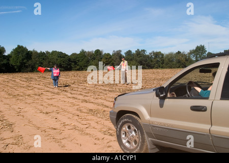 Mittelalter Mann und Frau halten Verkehr Flaggen an einem Connecticut USA fair Regie Autos parken in ein leeres Feld. Stockfoto