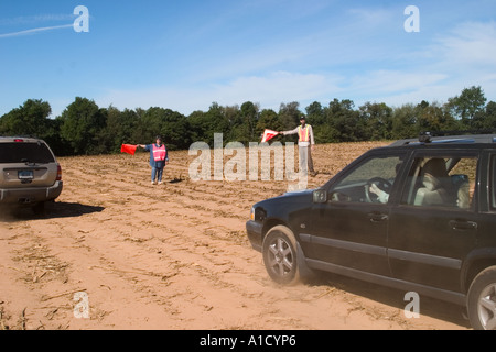 Mittelalter Mann und Frau halten Verkehr Flaggen an einem Connecticut USA fair Regie Autos parken in ein leeres Feld. Stockfoto