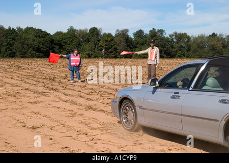 Mittelalter Mann und Frau halten Verkehr Flaggen an einem Connecticut USA fair Regie Autos parken in ein leeres Feld. Stockfoto