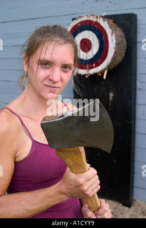 Junge weibliche Holz hacken Konkurrenten halten ihre Axt neben einer Axt werfen Ziel auf einer Messe in Connecticut, USA. Stockfoto