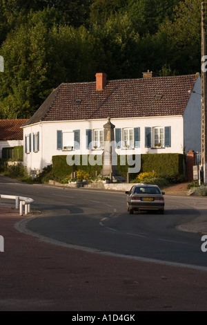 Kleinen weiß getünchten Häuschen am Rand des Dorfplatzes mit Centotaph oder Krieg-Denkmal außerhalb Fillievres-Pas-De-Calais Stockfoto