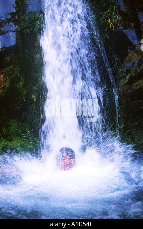 Abkühlung unter dem Wasserfall beim trekking Stockfoto