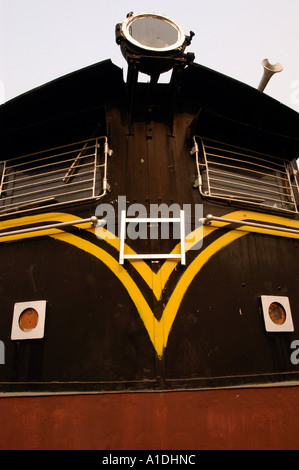 Vorderansicht einer schwarzen Indian Train Lokomotive mit charakteristischen gelben V-förmigen Streifen, einem großen oberen Scheinwerfer und vergitterten Kabinenfenstern. Stockfoto